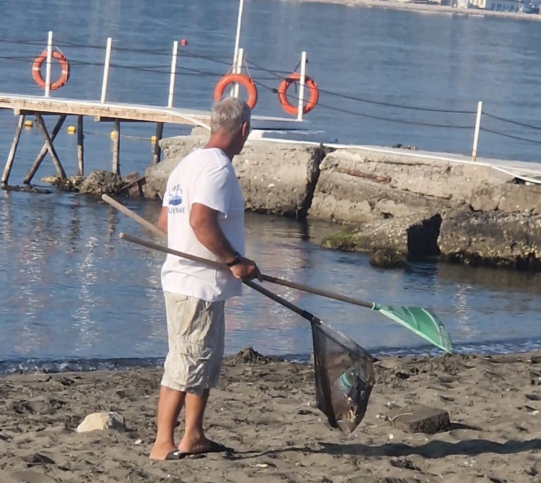 Il comune di Pozzuoli non pulisce: sulla spiaggia libera di Lucrino ci pensano i volontari – LE FOTO